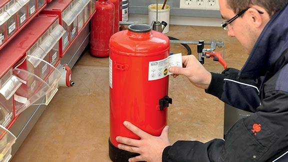 Firefighter attaching a label on a fire extinguisher