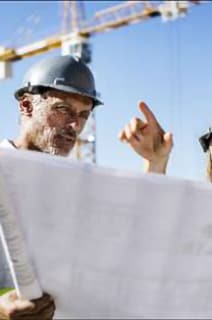 Two engineer in safety jackets having a discussion over a blueprint in an outdoor space